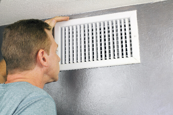 man looking into air vent
